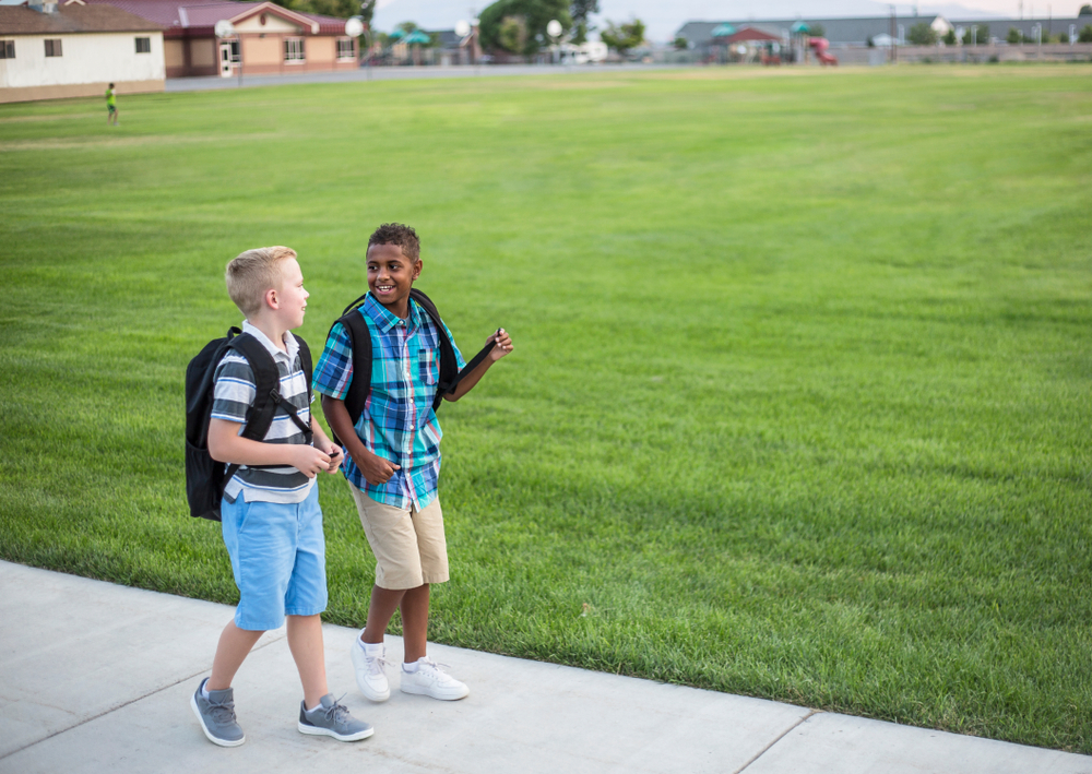 Two boys in backpacks walking and talking.