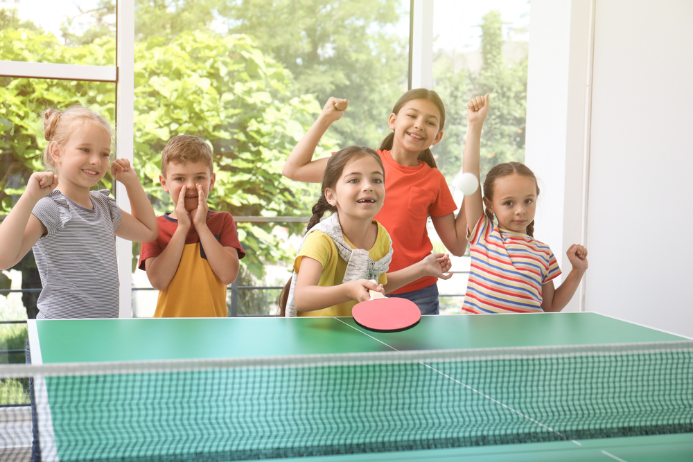 A group of kids playing table tennis.