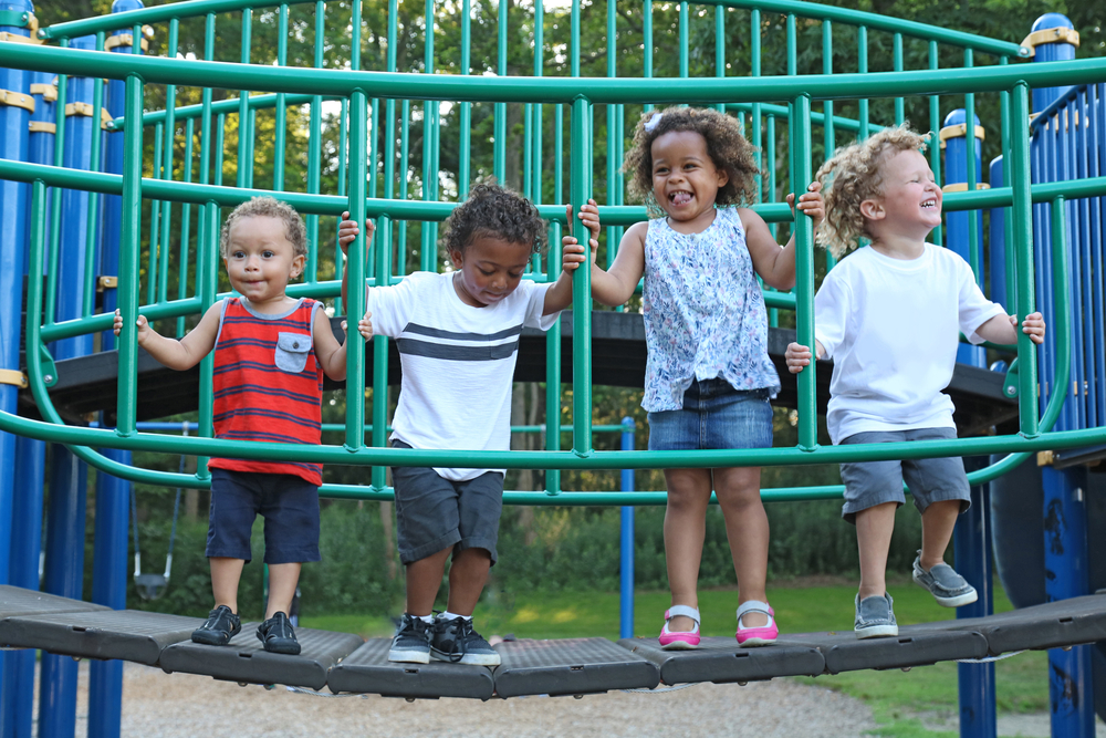 A group of kids playing on an outdoor jungle gym.