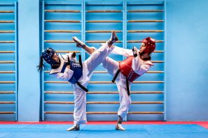 Two taekwondo athletes kicking each other.