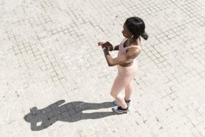 A woman in workout clothes checking her smartwatch outdoors.