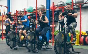 A woman jumping rope beside a group of people using stationary bikes at a gym.